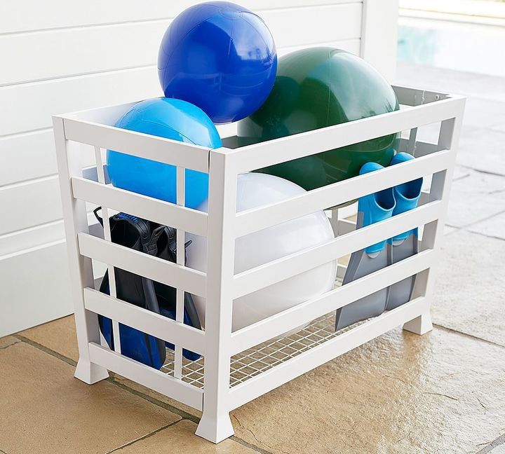 a white crate filled with blue and green balloons on the side of a building next to a door