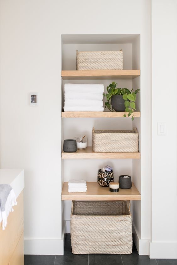 the shelves in this bathroom have baskets and towels on them, along with other items