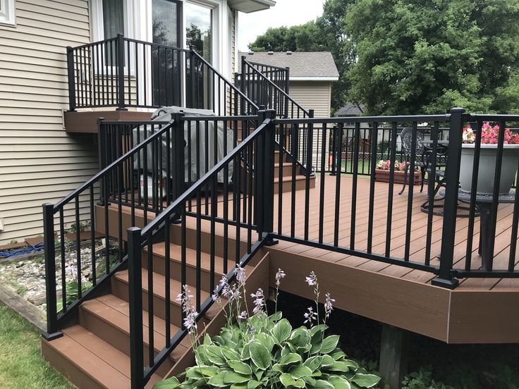 a deck with black railing and steps leading up to a house