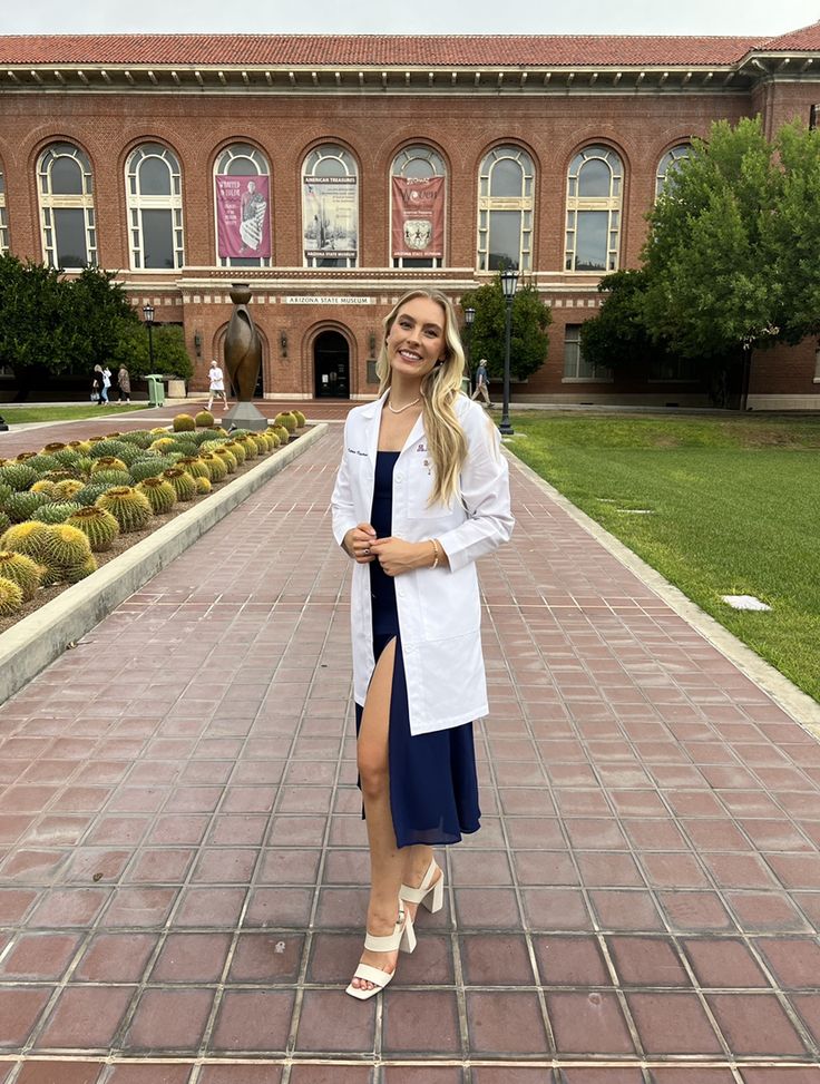 a woman is standing in front of a building wearing a white shirt and blue skirt