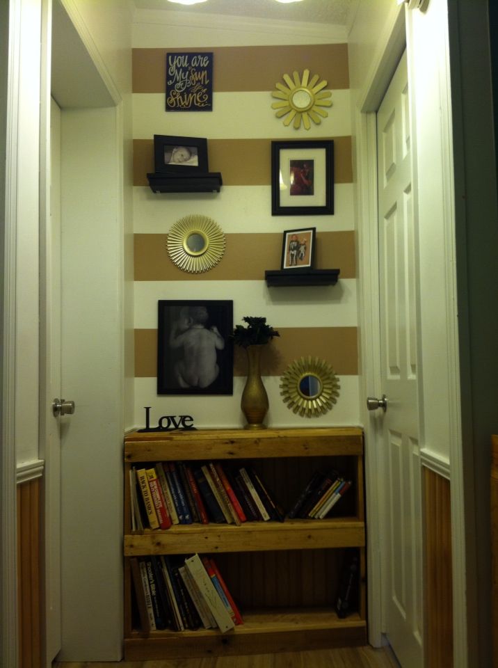 there is a bookshelf in the hallway with pictures on the wall above it