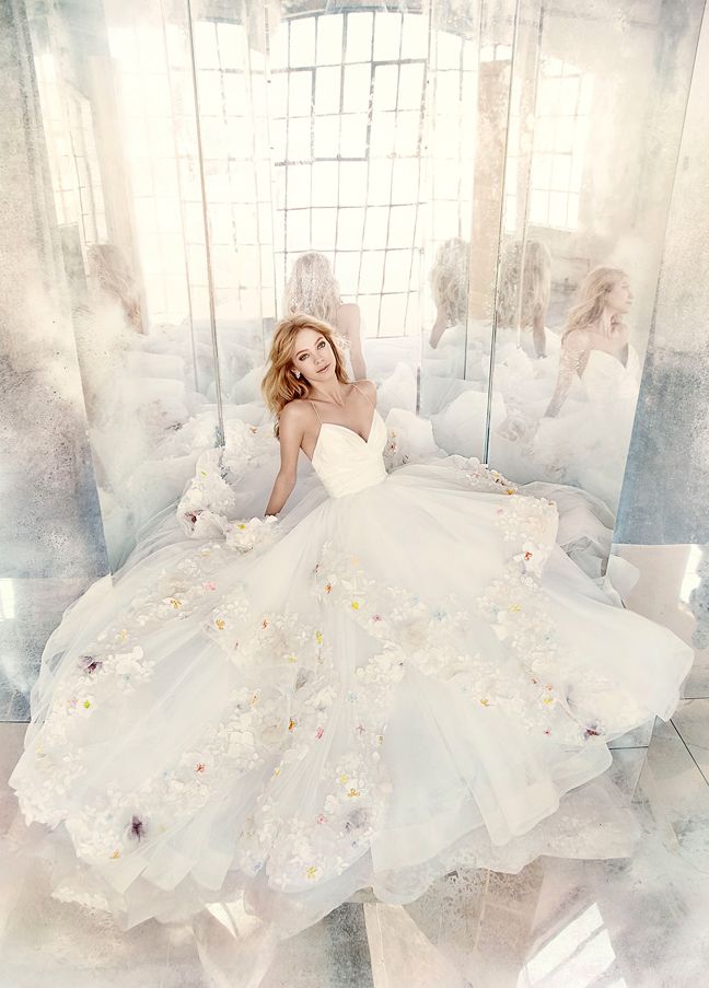 a woman in a wedding dress sitting on a bed with her reflection in the mirror