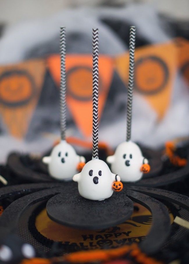 halloween cake with white frosting and black candles on top, decorated like ghostes