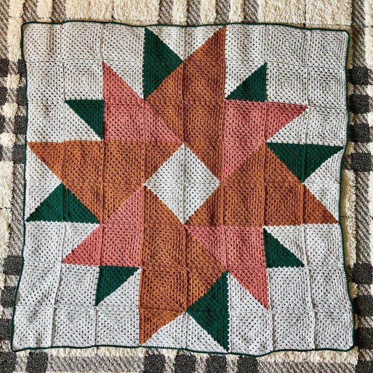 an orange and green star is on top of a white blanket with black checkers