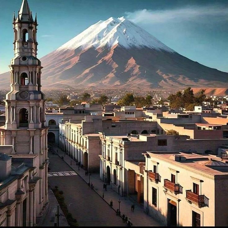 a tall tower with a clock on it's side in front of a mountain