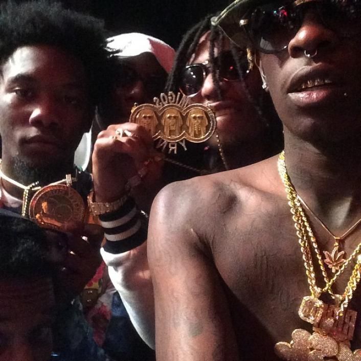 a group of young men wearing gold necklaces and holding up some small medallions