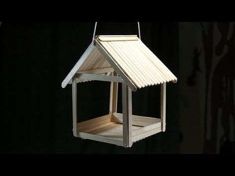 a white bird feeder hanging from a black background with the light shining on it's roof