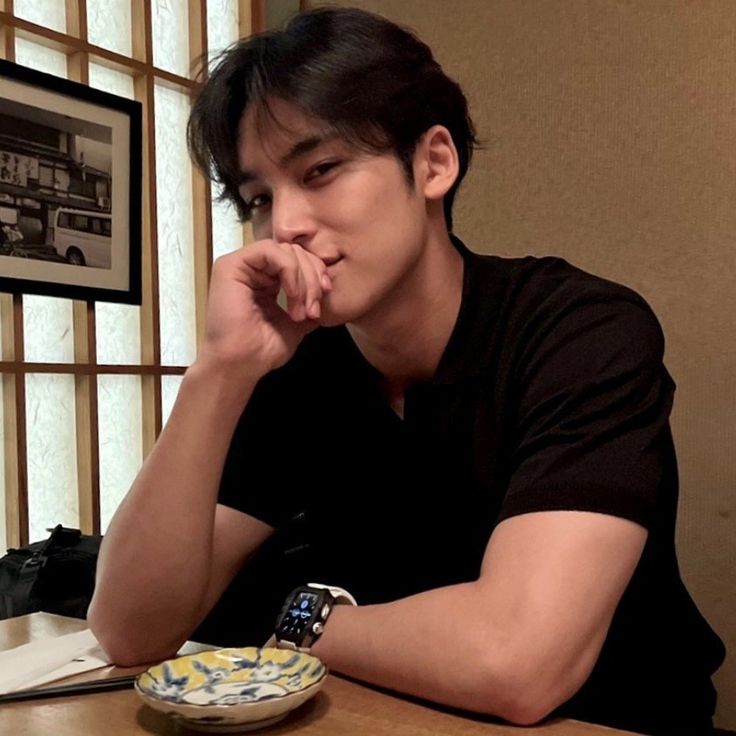 a young man sitting at a table with a plate in front of him and his chin resting on his hand