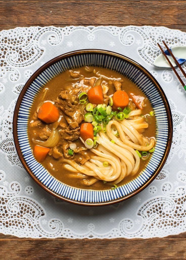 a bowl of soup with noodles, carrots and meat