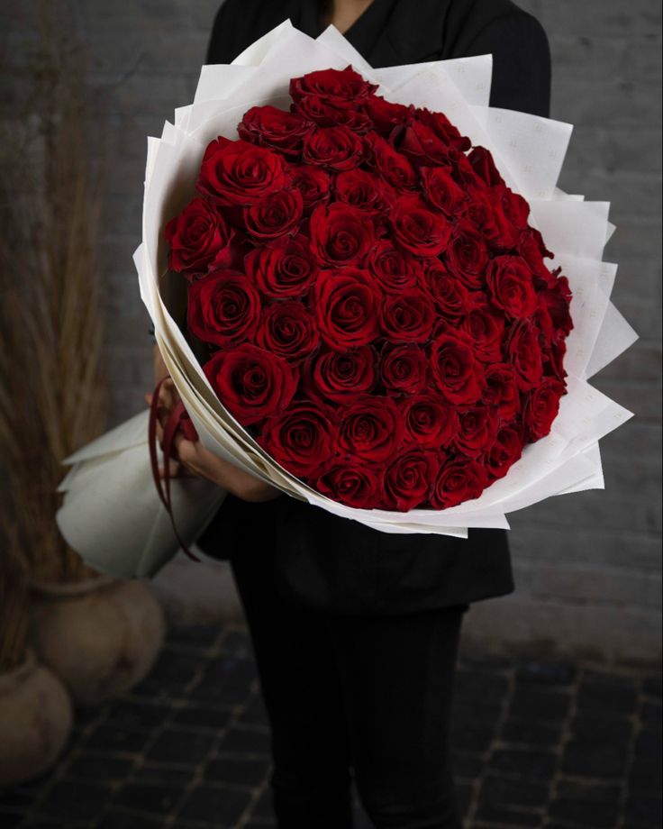 a woman holding a bouquet of red roses