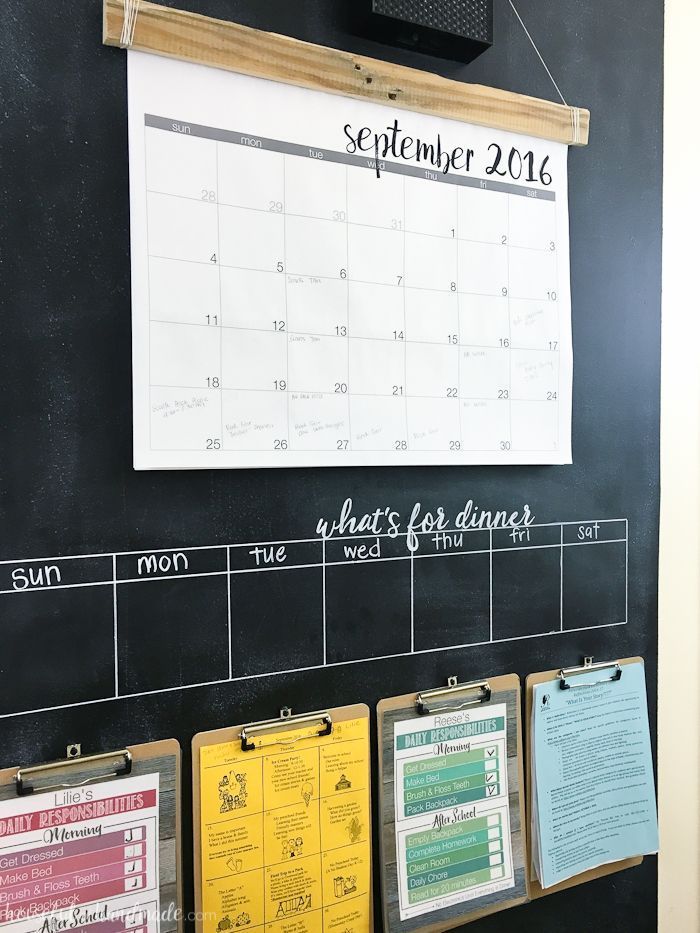 a chalk board with calendars hanging on it