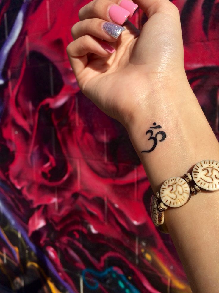 a woman's wrist with a tattoo that has an omen symbol on it