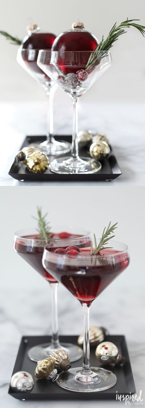 two glasses filled with red liquid and garnished with rosemary sprigs on black serving trays