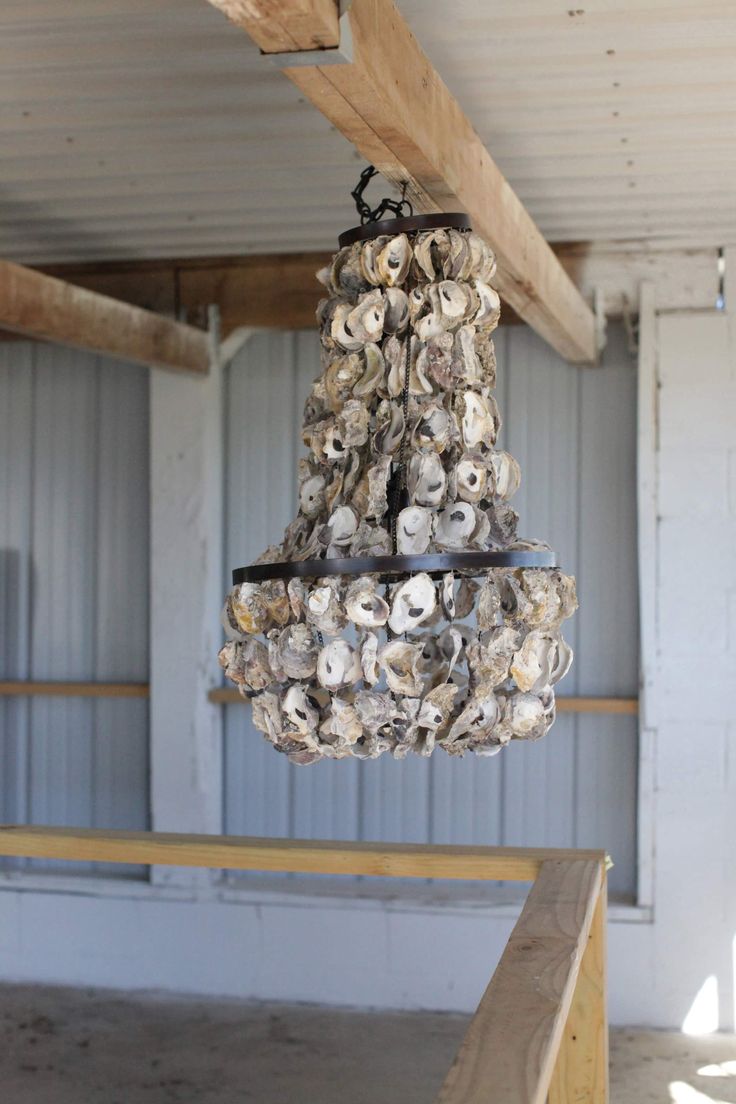 a chandelier made out of seashells hangs from the ceiling in an unfinished room