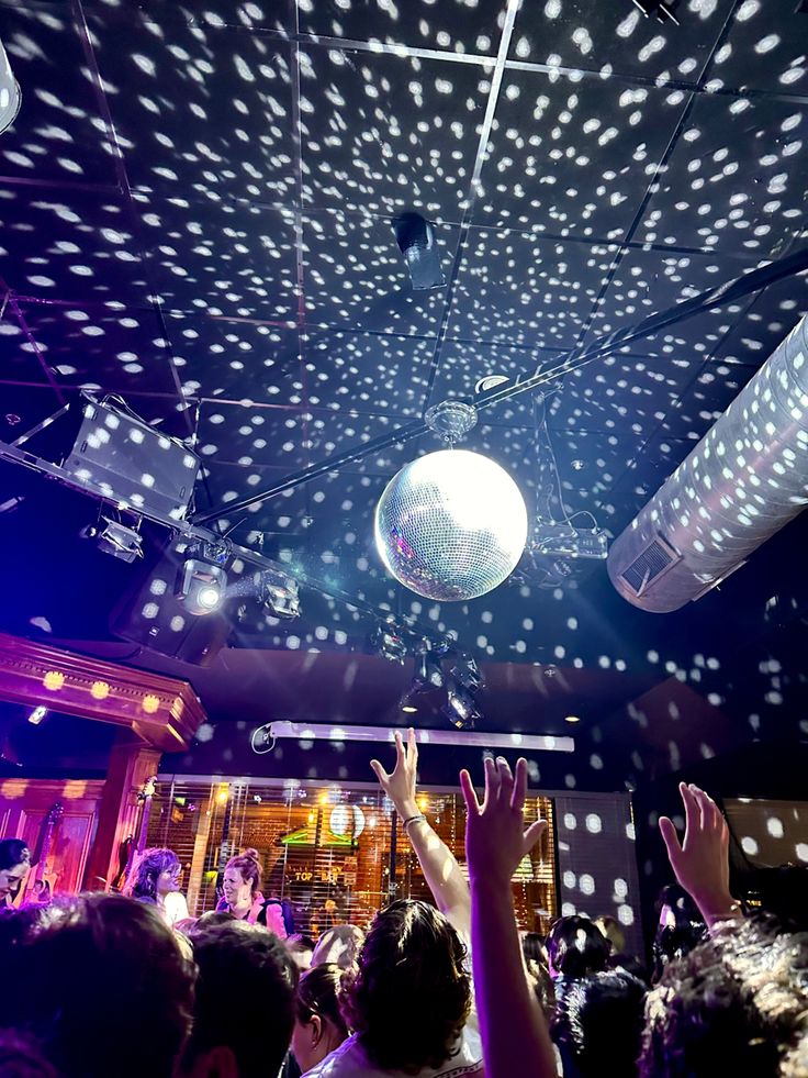 a disco ball is suspended from the ceiling at a party with people dancing around it