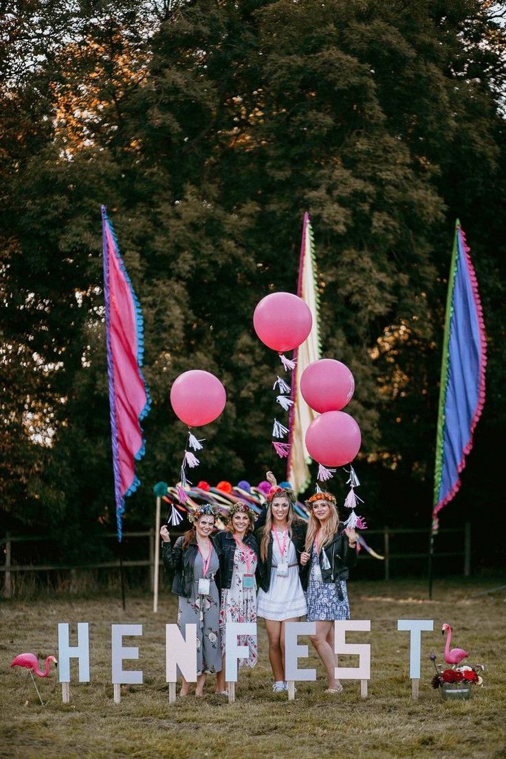 three girls standing in front of a sign with balloons and streamers all around them