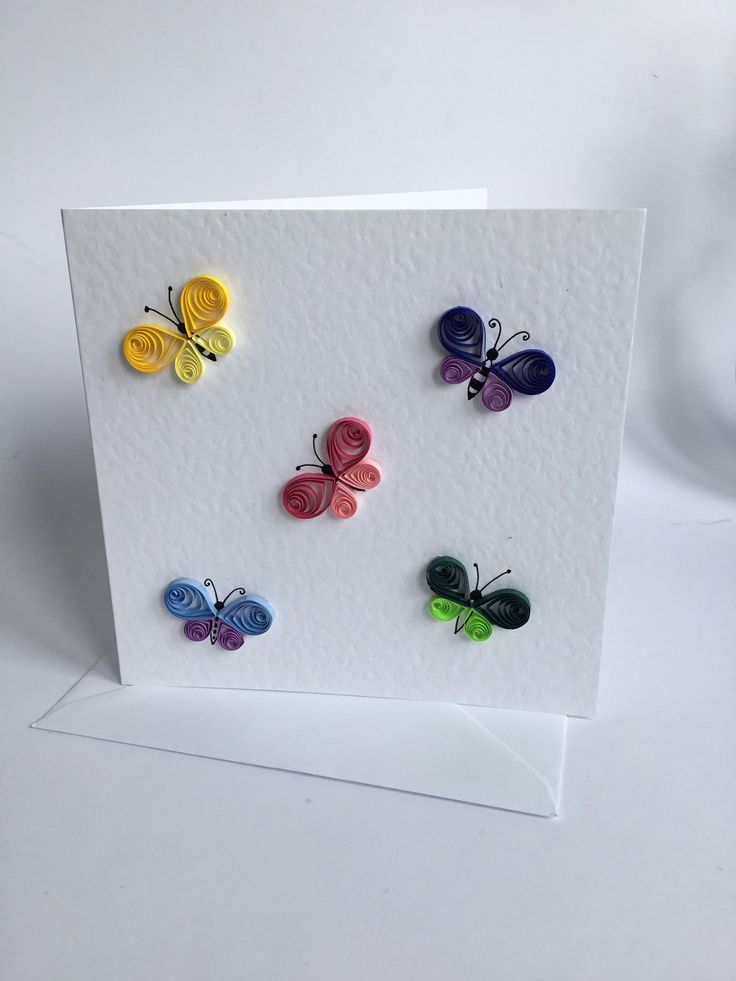 a card with four different colored butterflies on the front and one in the back, sitting on top of a white envelope