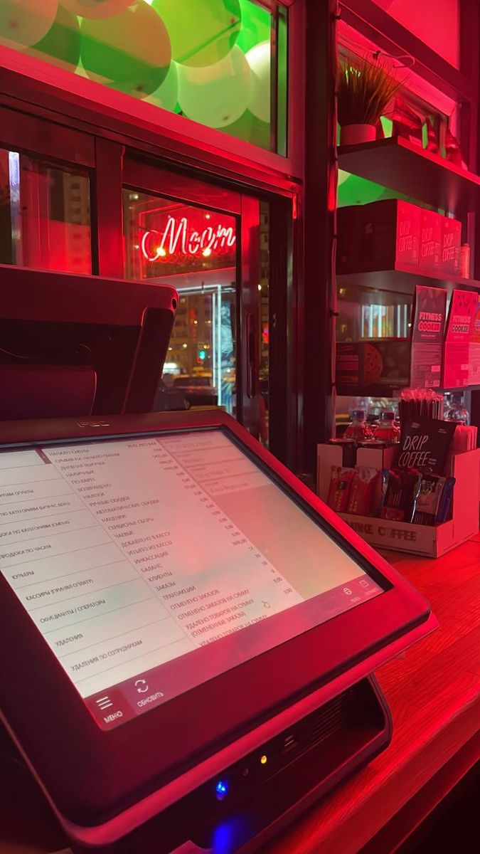 an electronic device sitting on top of a wooden table in front of a neon sign