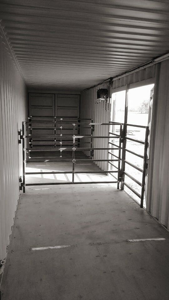 the inside of a storage unit with sliding doors and railings on both sides, looking out onto an empty parking lot