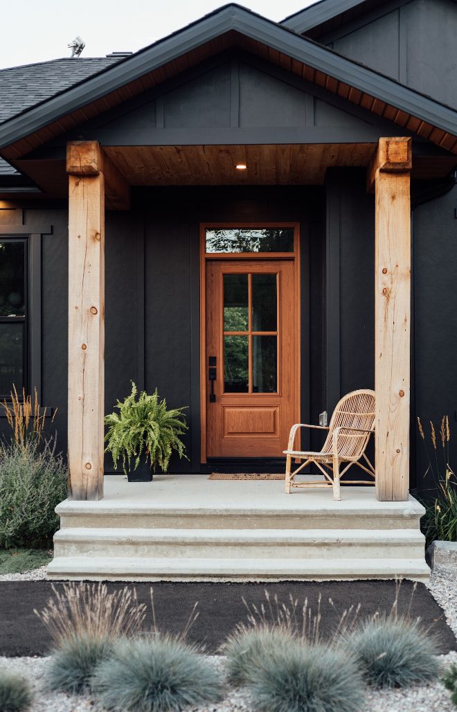 a chair sitting on the front porch of a house next to some plants and bushes