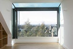 an empty room with a large window overlooking the city below and stairs leading up to it