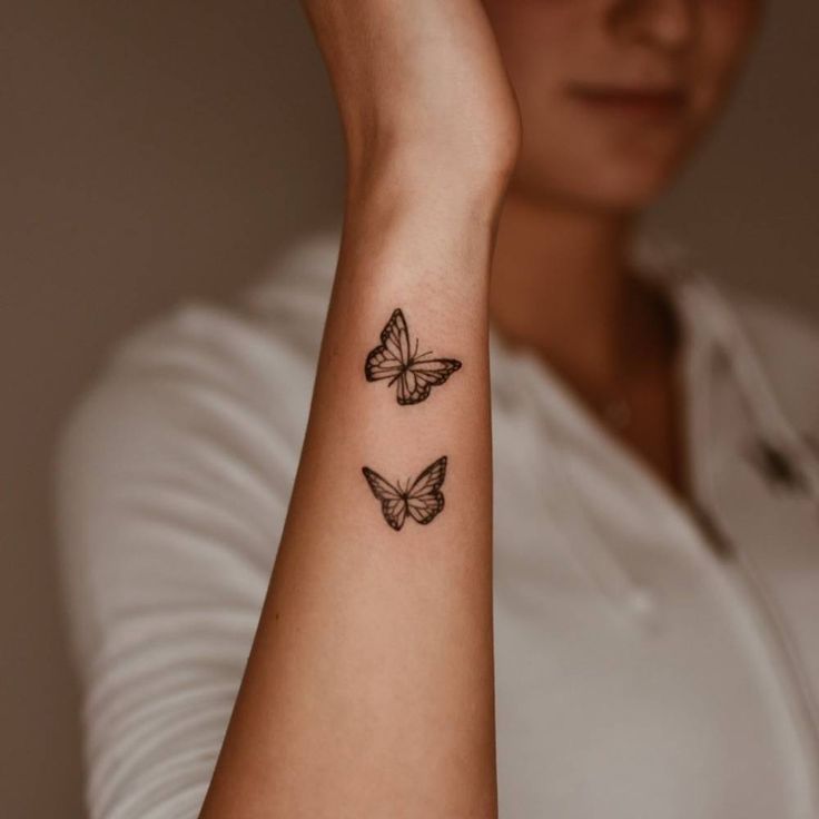 a woman's arm with two butterflies tattooed on the left side of her arm