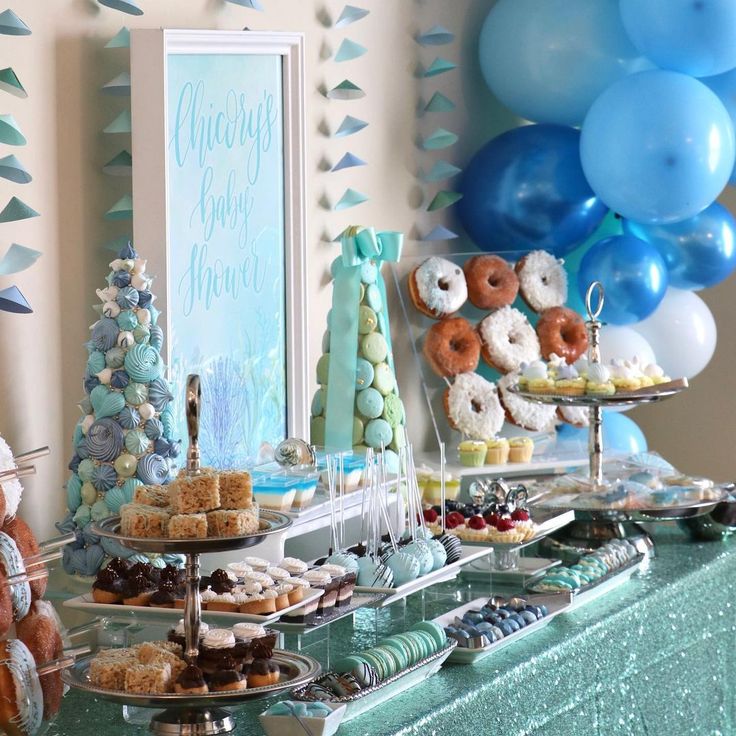 a dessert table with blue and white balloons, donuts, and other food items