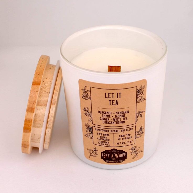 a white candle with a wooden lid next to it