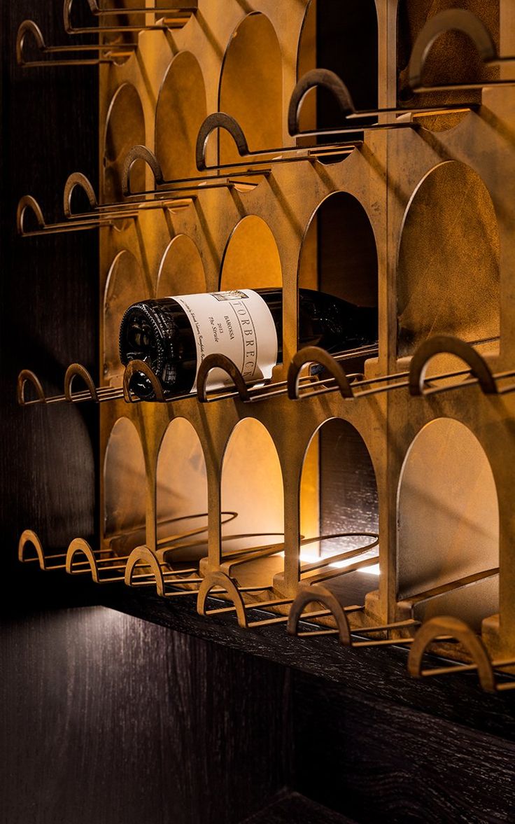 there is a wine rack with many bottles on the shelves and lights in the background