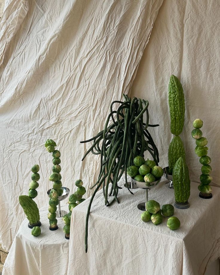 a table topped with lots of green plants and vases filled with watermelons