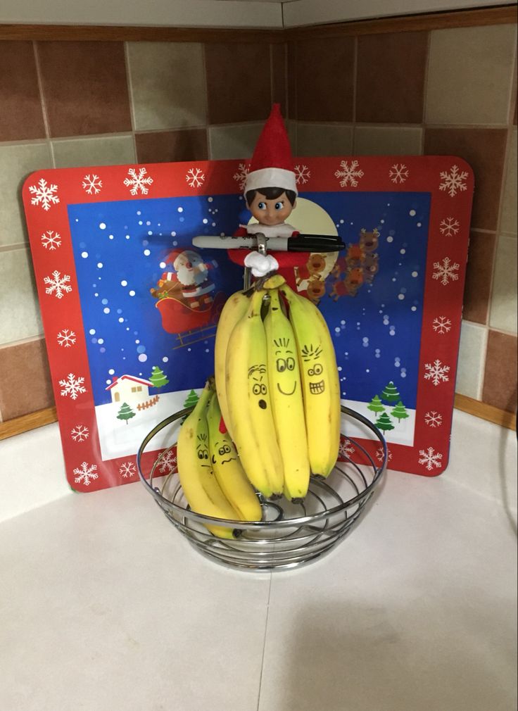 a elf is sitting on top of bananas in a bowl with santa's decorations