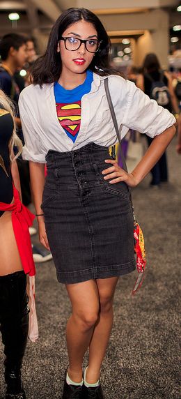 two women dressed in costumes standing next to each other at a convention or show, one wearing a superman shirt and the other with a supergirl on her chest