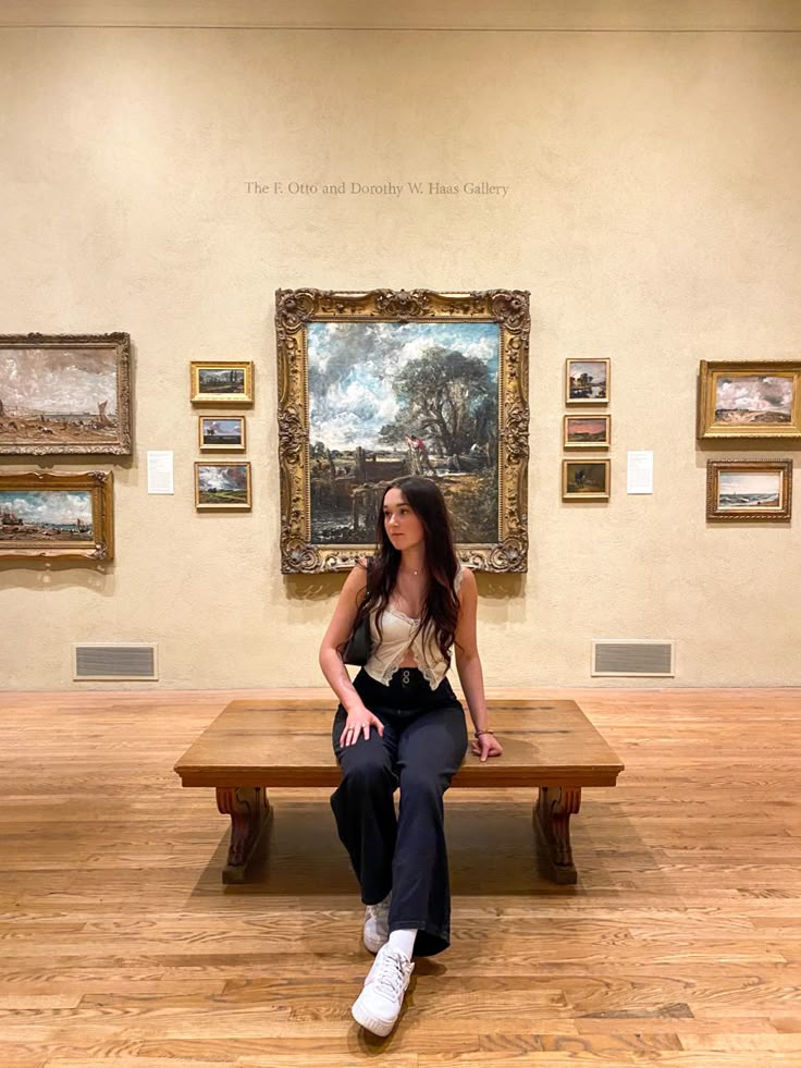 a woman sitting on a bench in an art gallery