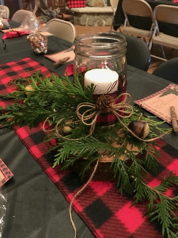 a table topped with a mason jar filled with candles and greenery next to other items