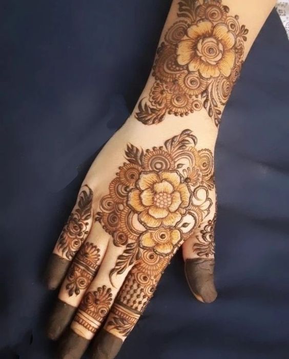 a woman's hand with henna tattoos on it and flowers in the middle