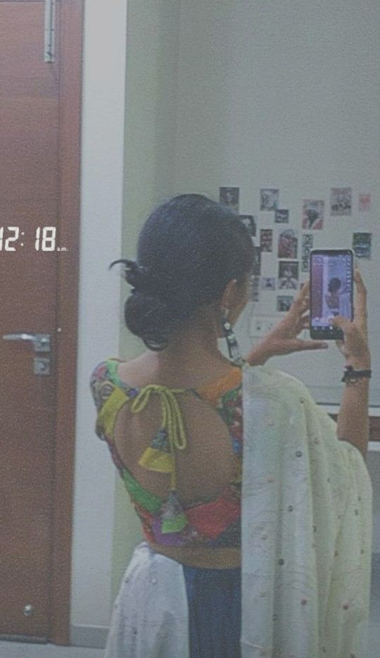 a woman standing in front of a mirror taking a selfie with her cell phone