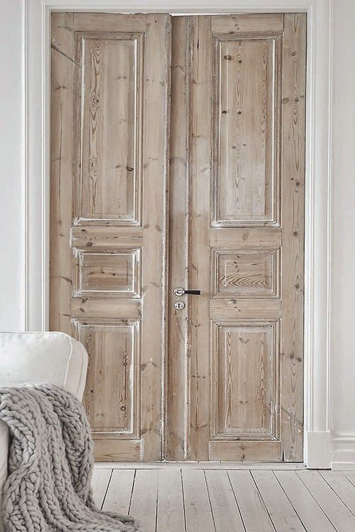 an open wooden door in a white room with a chair and rug on the floor