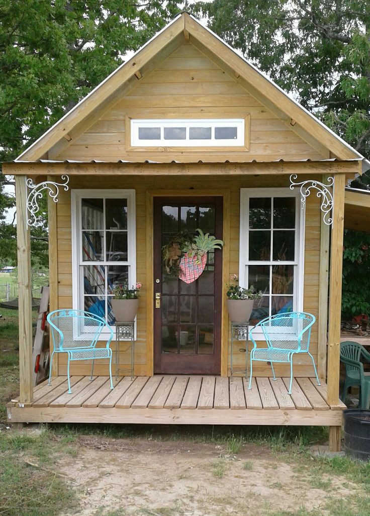 a small wooden house with two chairs on the porch