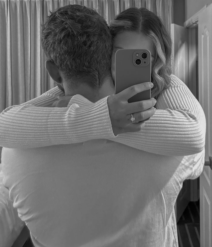 a man and woman taking a selfie in front of a mirror with their cell phone