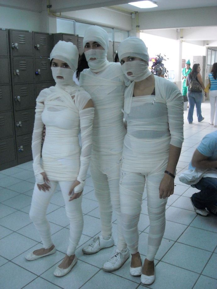 three people in white costumes standing next to each other on tiled floored area with lockers behind them