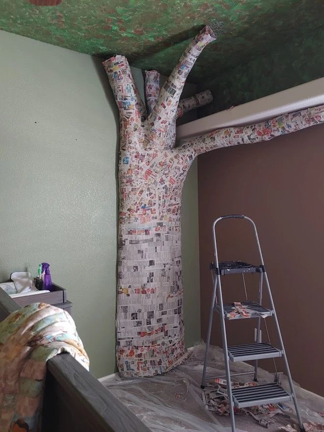 there is a tree that has been painted on the ceiling and it's next to a ladder