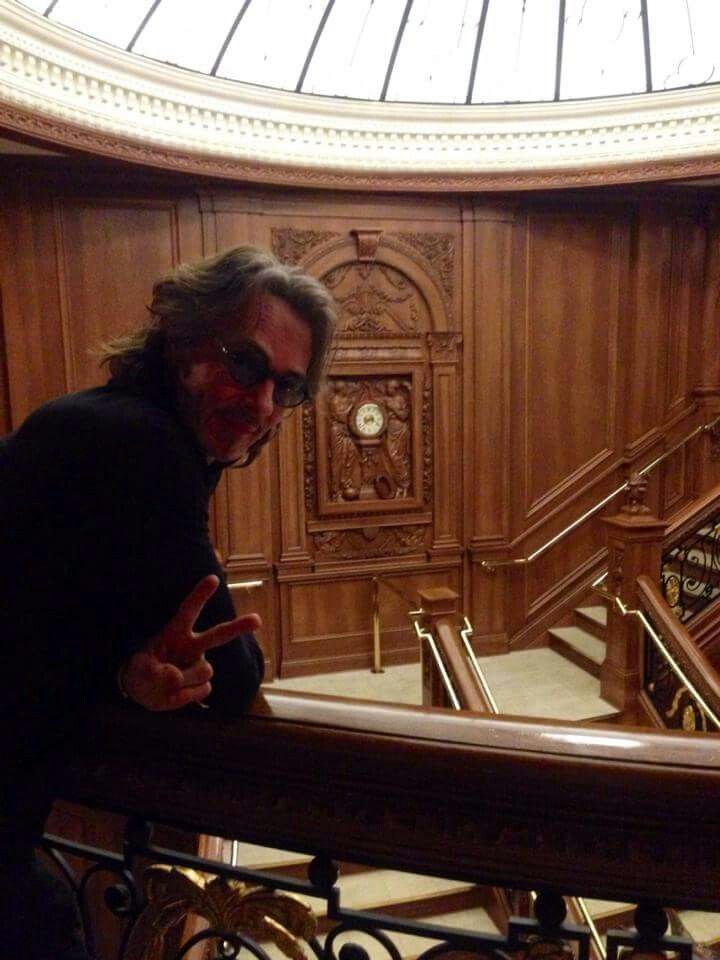 a man in black shirt standing on top of a stair case next to a clock