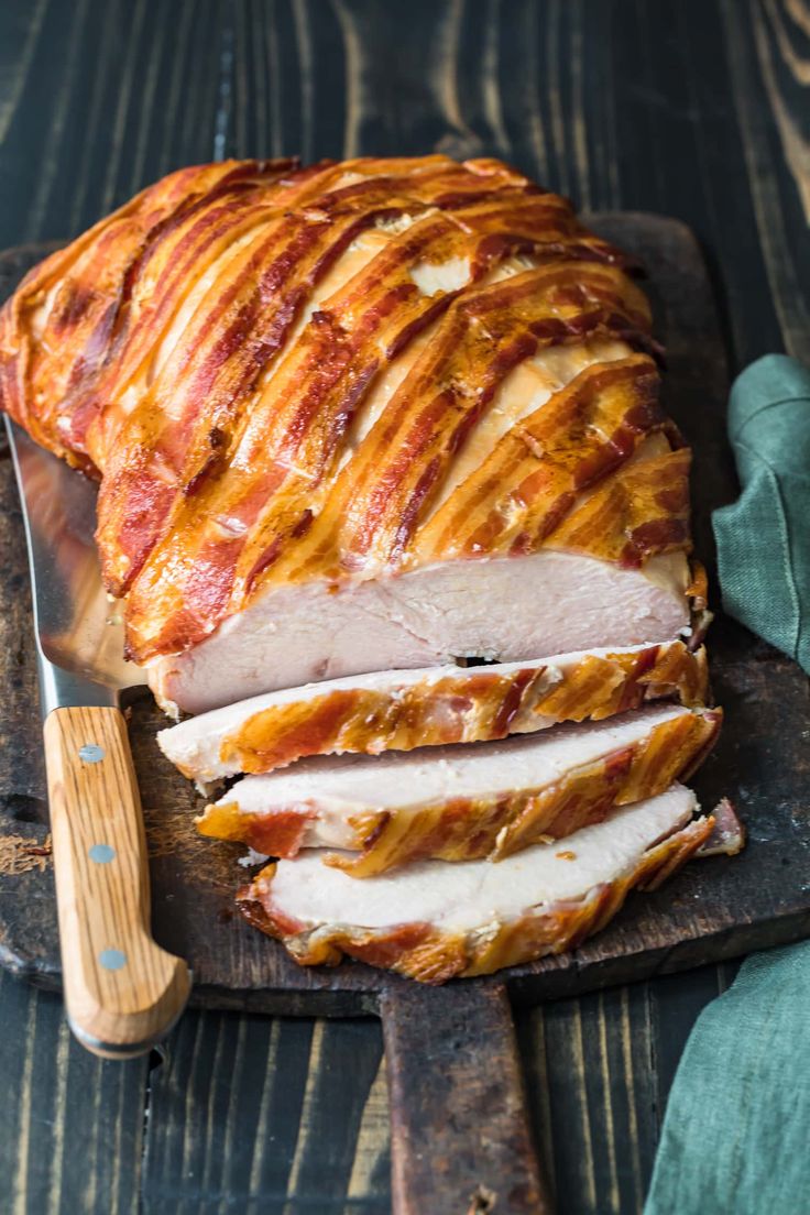 sliced ham sitting on top of a cutting board next to a knife