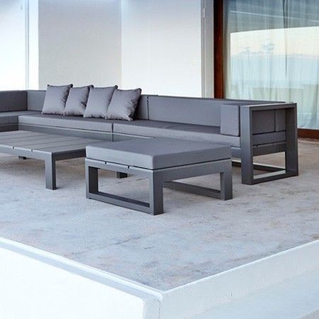 a couch and coffee table sitting on top of a cement floor next to a window