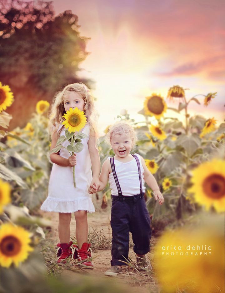 two young children are standing in a field of sunflowers