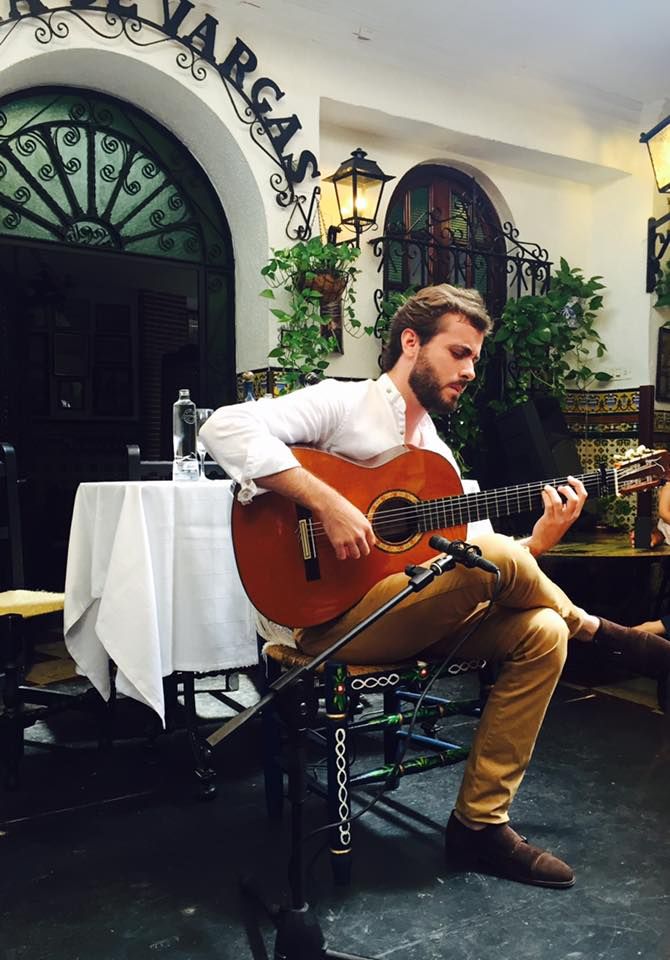 a man sitting at a table playing an acoustic guitar