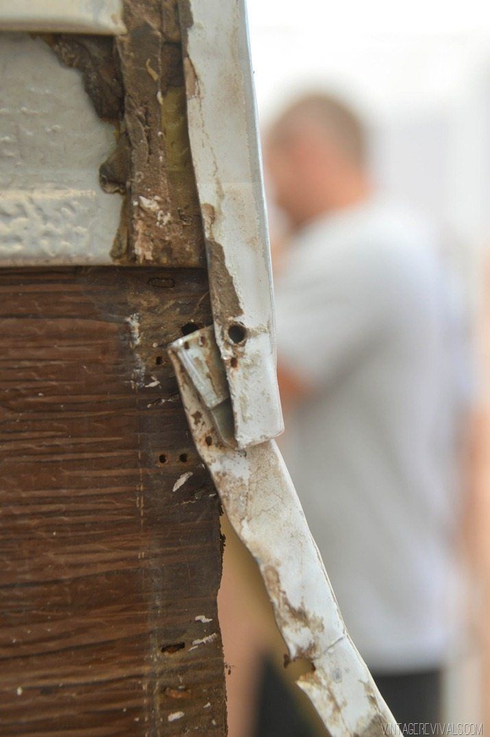 a man standing next to a wooden door with peeling paint on the outside and inside