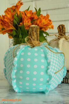 decorative pumpkins are sitting on a table with orange flowers in the vase behind them