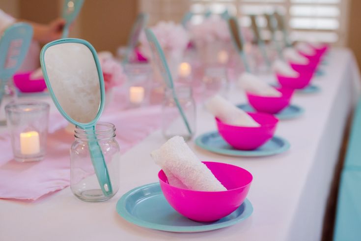 the table is set with pink and blue dishes