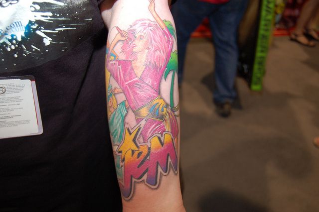 a person with a colorful tattoo on their arm holding a cell phone in her hand